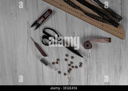 Collection of sewing tools and tailoring accessories including scissors, measuring tape, ruler, threads and buttons arranged on table. Concept of hand Stock Photo