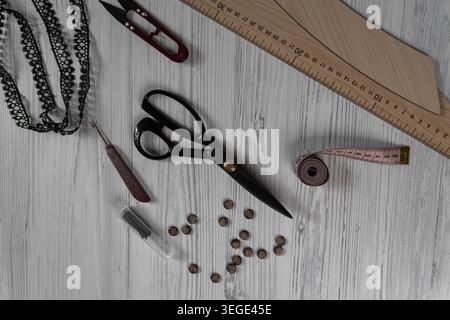 Collection of sewing tools and tailoring accessories including scissors, measuring tape, ruler, threads and buttons arranged on table. Concept of hand Stock Photo