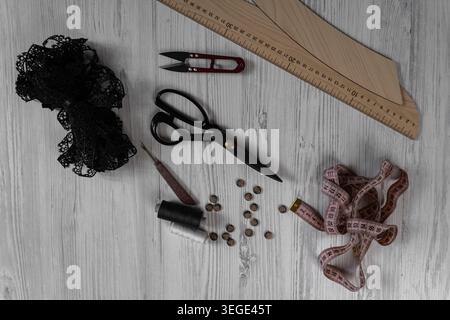 Collection of sewing tools and tailoring accessories including scissors, measuring tape, ruler, threads and buttons arranged on table. Concept of hand Stock Photo