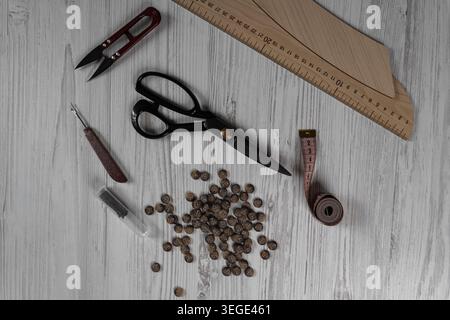 Collection of sewing tools and tailoring accessories including scissors, measuring tape, ruler, threads and buttons arranged on table. Concept of hand Stock Photo