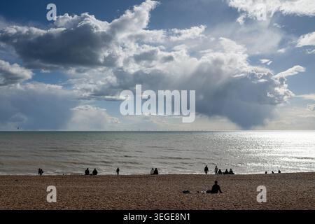 Silhouetted people on Brighton Beach beneath dramatic storm clouds gathering over the English Channel, Brighton, East Sussex, England, UK. Stock Photo