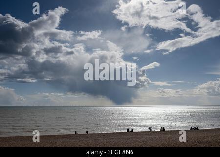 Silhouetted people on Brighton Beach beneath dramatic storm clouds gathering over the English Channel, Brighton, East Sussex, England, UK. Stock Photo