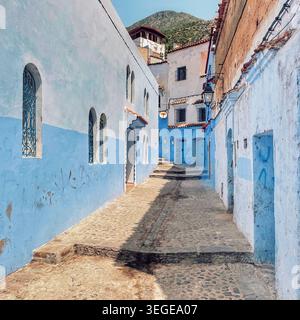 Narrow cobblestone street lined with blue‑painted houses and arched windows toward the hillside in the Blue City, 3 August 2025, Chefchaouen,Morocco. Stock Photo