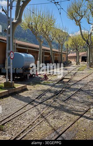 Vintage blue water tank wagon on a flatcar parked near manual track switch levers at the historic train station of Ferrocarril de Soller in Mallorca. Stock Photo