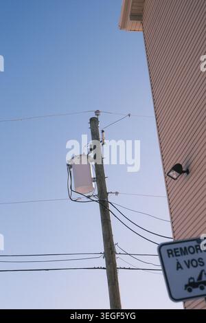 Utility pole with transformer and overhead wires against a clear blue sky in Quebec, Canada. Stock Photo