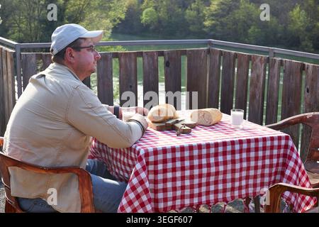 Man Using Smartphone During Rustic Countryside Breakfast Stock Photo