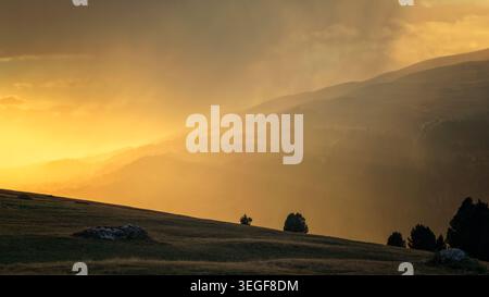 San Martin de Tor, Italy - 28.09.2024: A cinematic landscape capturing a powerful contrast between warm golden sunrays breaking through storm clouds a Stock Photo