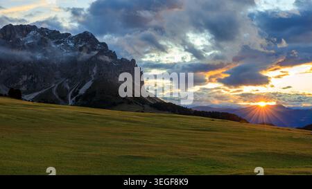 San Martin de Tor, Italy - 28.09.2024: A majestic wide-angle photograph capturing a powerful sunburst through heavy clouds over rugged mountain peaks Stock Photo