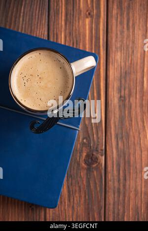 Mustache mug filled with hot coffee sitting on a blue notebook, creating a thoughtful gift concept for Father's Day or male celebrations, presented on Stock Photo