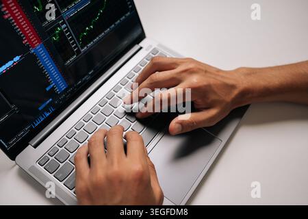 Top view of unrecognizable person trading online, monitoring stock market chart and financial data on laptop, analyzing investments and making Stock Photo