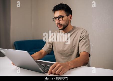 Pensive programmer male working typing code on laptop keyboard, showcasing process of software development and coding expertise. Stock Photo