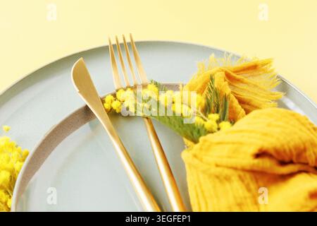 Elegant spring background with plate mimosa and golden cutlery Stock Photo