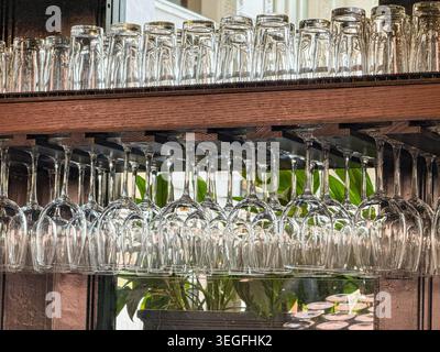 Empty wine glasses hanging from a rack in a bar Stock Photo