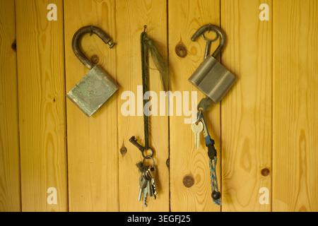 Old and modern padlocks with keys hanging on a wooden wall background Stock Photo