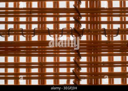 Extreme close-up detail of woven bamboo or rattan blinds showing horizontal and vertical natural wooden slats interlaced with dark binding wire or Stock Photo