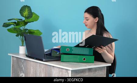 Confident businesswoman holding folder and thinking at office table Stock Photo