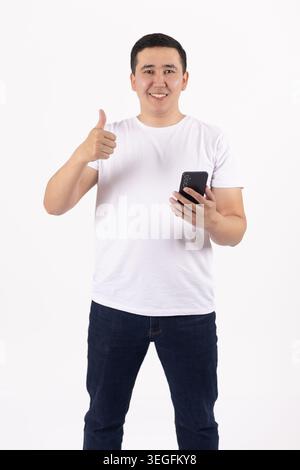 Happy handsome young man talking on smartphone holding thumb up Stock Photo