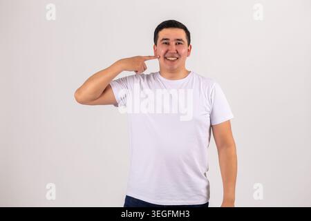 Handsome young man pointing finger at his throat showing gesture Stock Photo