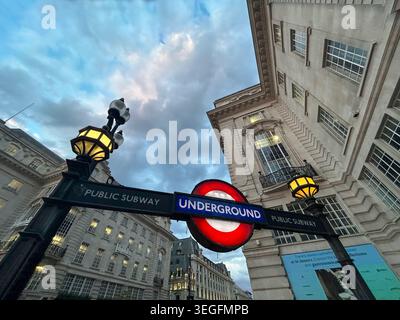 London, United Kingdom - 15th May 2026: The iconic red and blue London Underground tube sign and glowing traditional street lanterns at dusk, framed b Stock Photo