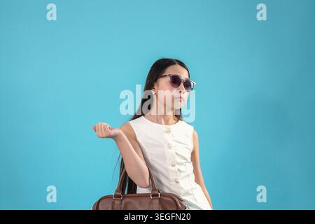 Young stylish woman wearing sunglasses posing standing on blue background Stock Photo