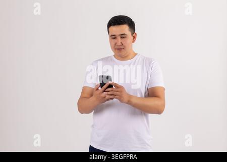 Handsome young man using mobile smartphone reading screen smiling Stock Photo