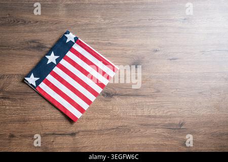 Folded American flag napkin on wooden table with copy space. Patriotic background for Fourth of July and USA holiday concepts. Stock Photo