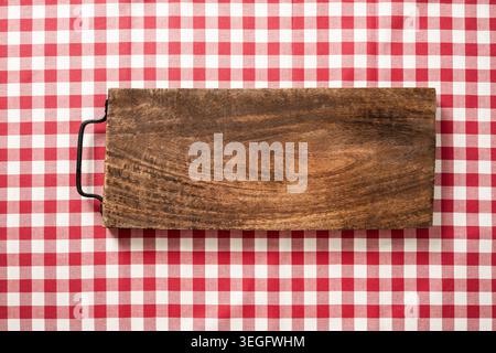 Rustic wooden board on red checkered tablecloth top view summer picnic BBQ background. Copy space American style outdoor concept Stock Photo