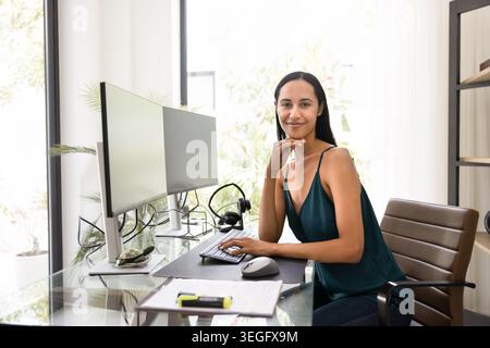 Confident woman working at dual monitor home office Stock Photo
