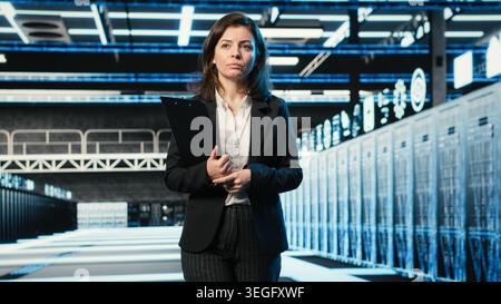 Inspecting hardware, blue wireframe mesh rackmounts and manager in data center. Looking at AR data streams, digital twin simulation and system administrator walking through server hub rows Stock Photo