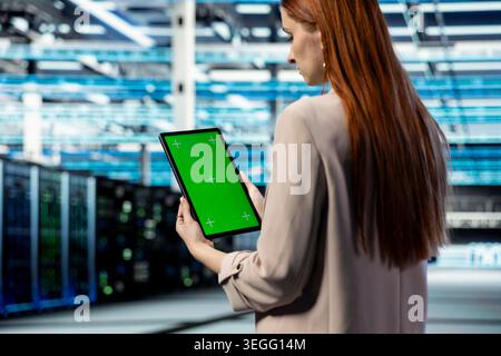 Green screen mockup tablet used by data center engineer managing IT infrastructure systems. Worker using chroma key isolated screen device in industry 4.0 server farm, technology concept Stock Photo