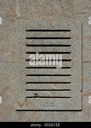 Minimalist stone ventilation opening with horizontal slits and textured surface, architectural detail with clean lines. Stock Photo