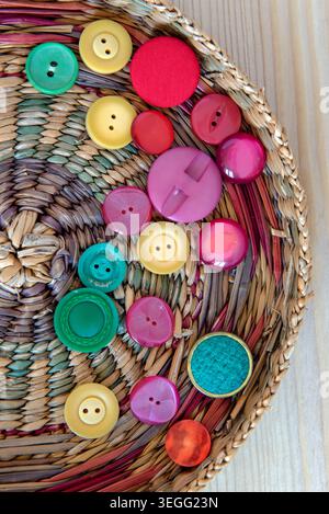 Colourful mixed colour vintage buttons on basket lid. Yellow, red and green. Stock Photo