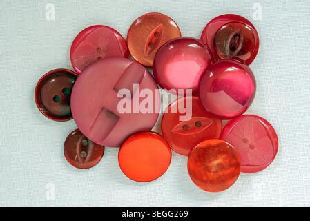 Mixed red vintage buttons on white cotton background Stock Photo