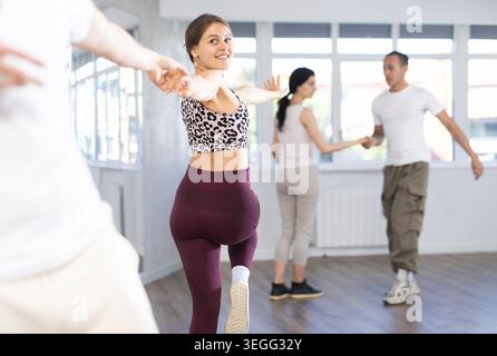 Group of young active sports people practicing rock and roll dance in dance hall Stock Photo