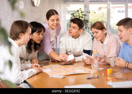 Carefree girl playing board game with friends at table Stock Photo