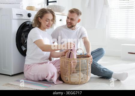 Happy couple doing laundry together at home Stock Photo