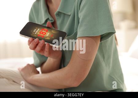 Diabetes. Woman with sensor checking glucose level via smartphone app, closeup Stock Photo