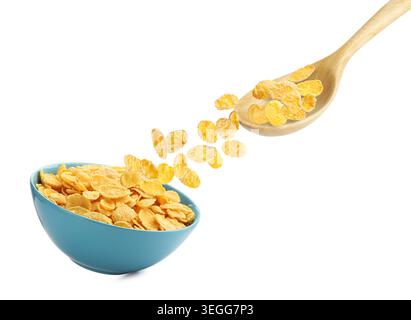 Corn flakes falling from spoon into bowl against white background Stock Photo