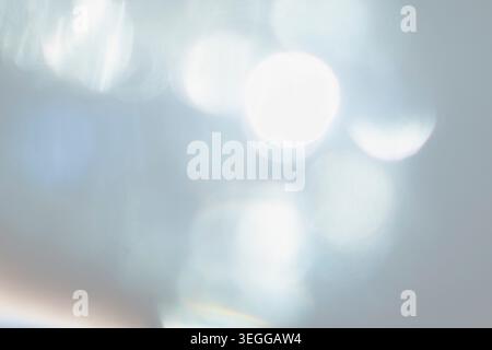 Defocused bright white bokeh lights on pale blue background Stock Photo