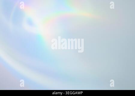 Soft pastel iridescent light leak with subtle rainbow flare on light blue background Stock Photo