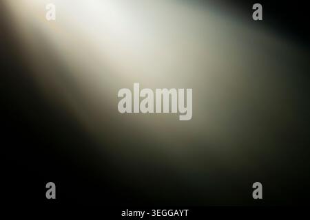 Bright warm light rays shining diagonally across a dark abstract background creating a soft glowing overlay Stock Photo