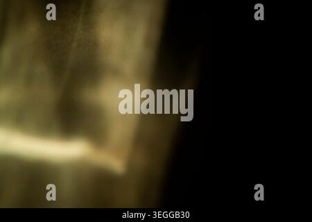 Abstract sepia golden light leak texture fading into dark black background Stock Photo