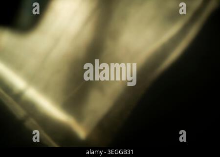 Bright golden abstract light leak with diagonal glowing edges on black Stock Photo