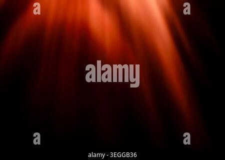 Intense red and orange glowing light rays falling on dark background Stock Photo