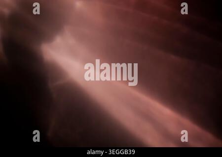 Warm copper red light rays shining diagonally across a dark abstract background Stock Photo