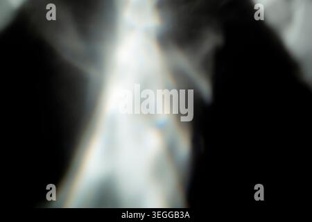 Soft blurred white light rays and subtle lens flare effect on a black background Stock Photo