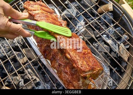 Pork ribs grilling. Outdoor cookout featuring grilled pork ribs with golden crust and smoky flavor in summer Stock Photo