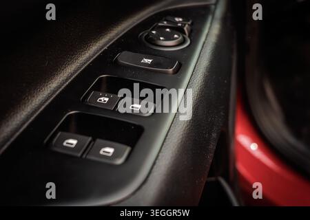 Close-up of a car interior door panel with electric window switches, mirror adjustment controls, and tactile buttons, emphasizing convenience features Stock Photo