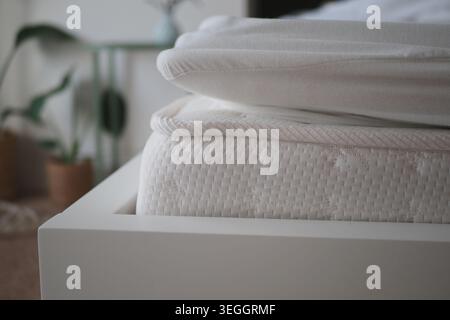 Two layers of bedding on a bed frame in a room Stock Photo