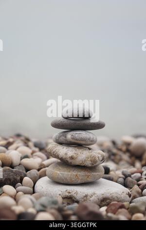 Balanced stone stack on pebble beach near water Stock Photo